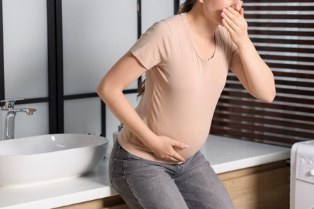 Pregnant woman suffering from nausea in bathroom, closeup. Toxicosis during pregnancy