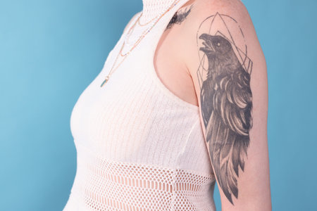 Young woman with tattoos posing on light blue background, closeupの写真素材
