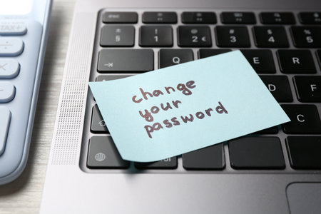 Note with phrase Change your password and laptop on white wooden desk, closeupの写真素材