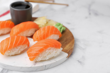 Delicious nigiri sushi with salmon, wasabi, ginger and soy sauce on white marble table, closeup. Space for textの写真素材
