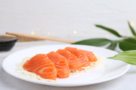 Fresh salmon sashimi with sliced radish on light gray table, closeupの写真素材