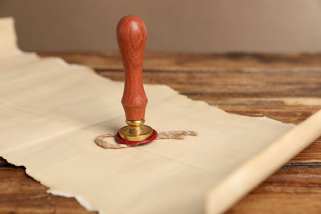 Old paper scroll and wax stamp on wooden table, closeupの写真素材