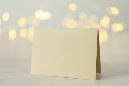 Blank card on white wooden table against blurred background, bokeh effect. Mockup for designの写真素材