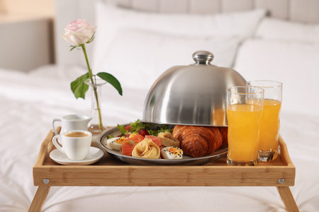 Tray with delicious breakfast and rose on bed in hotel room, closeupの写真素材
