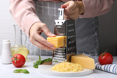 Woman grating cheese at white tiled table, closeupの写真素材