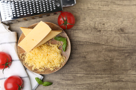 Grated cheese, grater and products on wooden table, flat lay. Space for textの写真素材