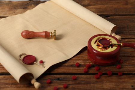 Old paper scroll, stamp and pieces of wax on wooden table, closeupの写真素材