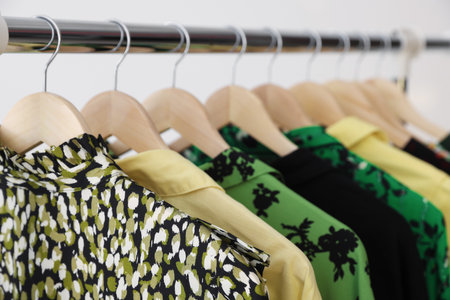 Different clothes hanging on rack against light background, closeupの写真素材