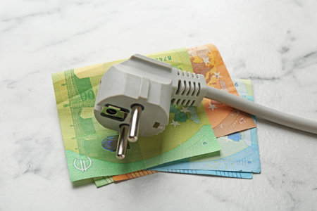 Electrical wire with plug and euro banknotes on white marble table, closeupの写真素材