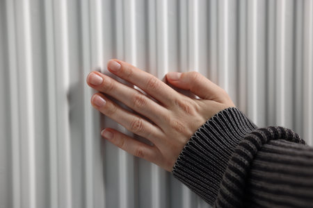 Woman warming her hand near radiator indoors, closeupの写真素材