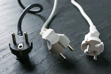 Electrical wires with plugs on black table, closeup