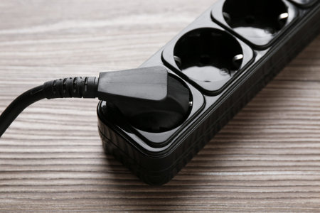 Power strip with electrical plug on wooden table, closeup
