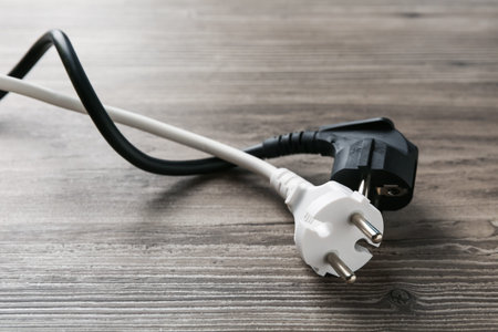 Electrical wires with plugs on wooden table, closeup
