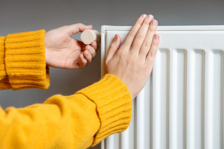 Woman adjusting temperature of radiator indoors, closeupの写真素材