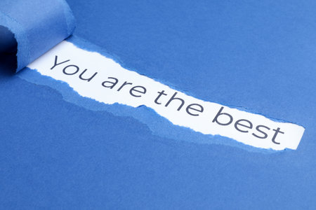 Winner. Phrase You Are The Best on white background, view through hole in torn blue paperの写真素材