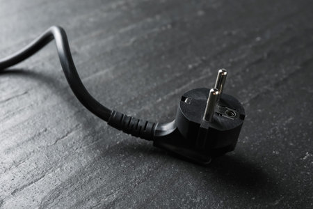 Electrical wire with plug on black table, closeup