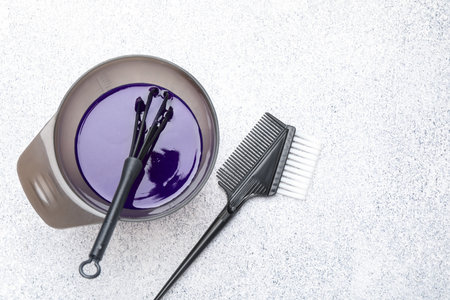 Hair dyeing product in bowl and hairdresser's tools on light gray table, flat lay. Space for textの写真素材