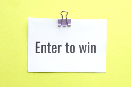 Paper note with phrase Enter To Win on yellow background, top viewの写真素材