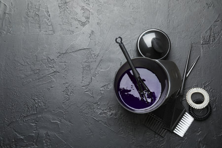 Hair dyeing product in bowl and different hairdresser's tools on black table, flat lay. Space for textの写真素材
