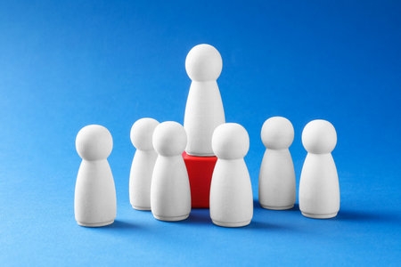 Winner. Human figures, wooden one on red cube against light blue backgroundの写真素材