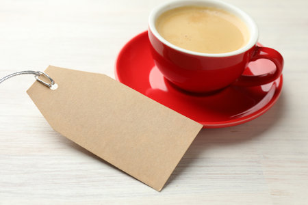 Blank card and cup of coffee on white wooden table, closeup. Mockup for designの写真素材