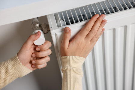 Woman adjusting temperature of radiator indoors, closeupの写真素材