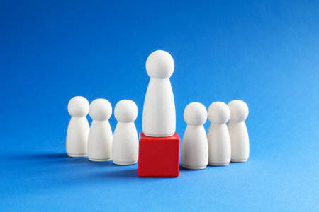 Winner. Human figures, wooden one on red cube against light blue backgroundの写真素材