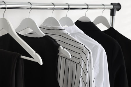 Different stylish clothes hanging on rack indoors, closeupの写真素材