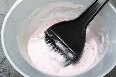Hair dyeing product in bowl and brush on black background, closeupの写真素材