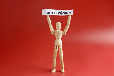 Human figure holding paper note with phrase I Am A Winner on red backgroundの写真素材