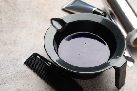 Hair dyeing product in bowl and different hairdresser's tools on light gray table, closeupの写真素材