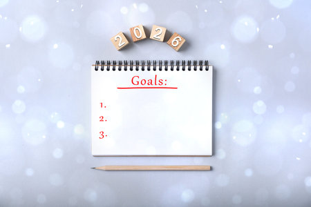 New 2026 Year Goals. Inscription in notebook and cubes with numbers on light gray background, top view. Bokeh lightsの写真素材