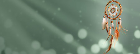 Dream catcher with feathers on sage background, bokeh lights. Banner design