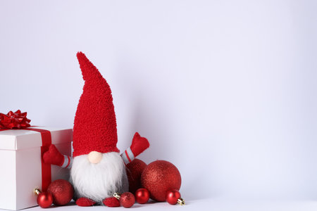 Funny Christmas gnome, gift box and festive decor on light gray background, space for textの写真素材