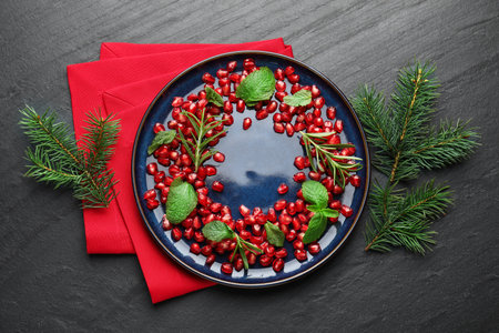 Christmas food. Pomegranate seeds, mint, rosemary and fir tree branches on dark textured table, flat layの写真素材
