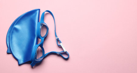 Swim cap and goggles on pink background, top view. Space for textの写真素材