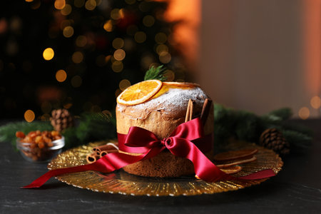 Christmas food. Delicious Panettone cake, ingredients and festive decor on black table against background with blurred lights, closeup. Bokeh effectの写真素材