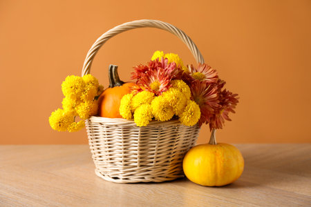 Beautiful autumn composition with flowers and pumpkins on wooden table against orange backgroundの写真素材