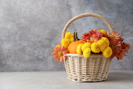 Beautiful autumn composition with flowers and pumpkin on light table. Space for textの写真素材