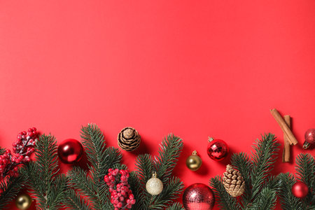 Flat lay composition with fir tree branches and Christmas decor on red background. Space for textの写真素材