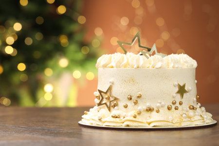 Delicious cake with Christmas decor on wooden table against blurred lights, closeup. Space for textの写真素材