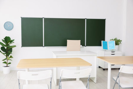 Green chalkboard and stylish furniture in classroom. Mockup for designの写真素材