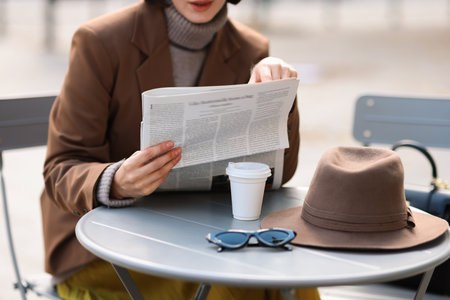 Woman in suit reading newspaper at table in outdoor cafe, closeupの写真素材
