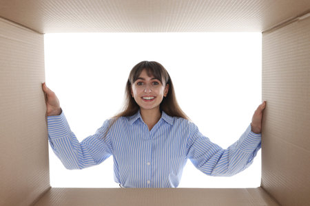 Woman looking into cardboard box against white background, view from inside package