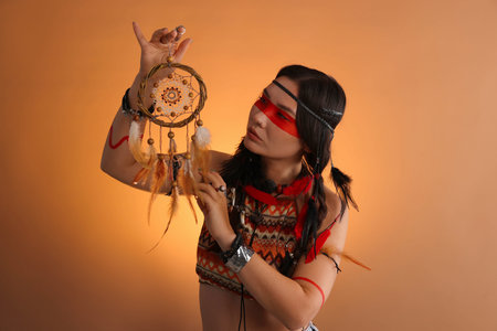 Shaman woman with face painting and dreamcatcher on orange gradient background