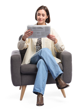 Beautiful woman reading newspaper and sitting on armchair against white backgroundの写真素材