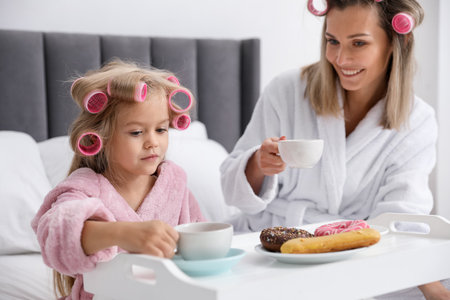 Mother and daughter having tea party on bed at homeの写真素材