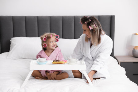 Mother and daughter having tea party on bed at homeの写真素材