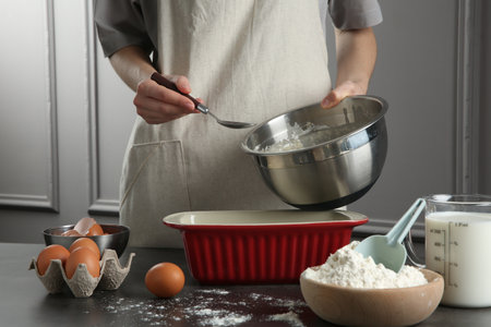 Woman with bowl of liquid dough at gray table in kitchen, closeupの写真素材