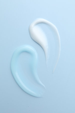 Samples of different cosmetic products on light blue background, flat layの写真素材